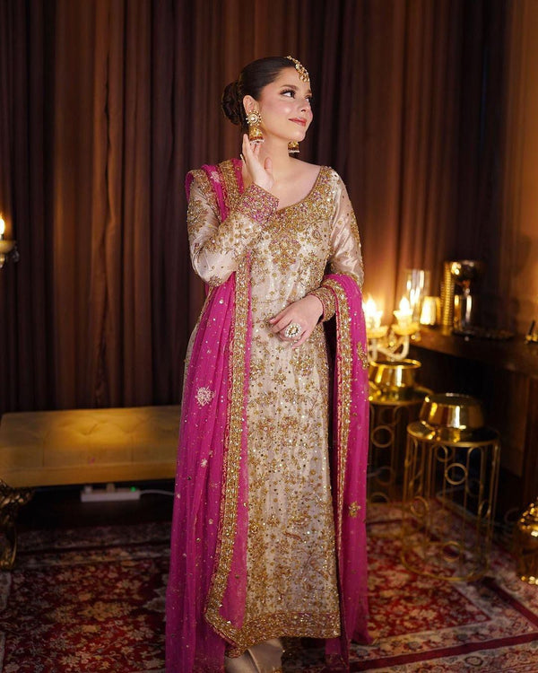 Haris Shakeel Gold & Pink pakistani indian wedding bridal dress, mehndi nikkah oufits guest suits
Product Description: Haris Shakeel embodies a white color on an net, which features intricate embroidery inspired by natures floral composition all over. Further layered with mesmerizing embellishments of sequins, pearls, and crystals. The outfit is paired with a modern look flared pants, and a sophisticatedly embroidered dupatta concluded with minimalistic borders, making this ensemble just the perfect choice