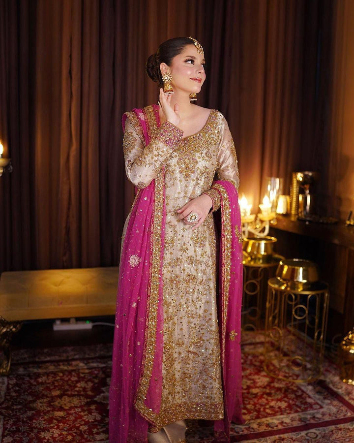 Haris Shakeel Gold & Pink pakistani indian wedding bridal dress, mehndi nikkah oufits guest suits
Product Description: Haris Shakeel embodies a white color on an net, which features intricate embroidery inspired by natures floral composition all over. Further layered with mesmerizing embellishments of sequins, pearls, and crystals. The outfit is paired with a modern look flared pants, and a sophisticatedly embroidered dupatta concluded with minimalistic borders, making this ensemble just the perfect choice